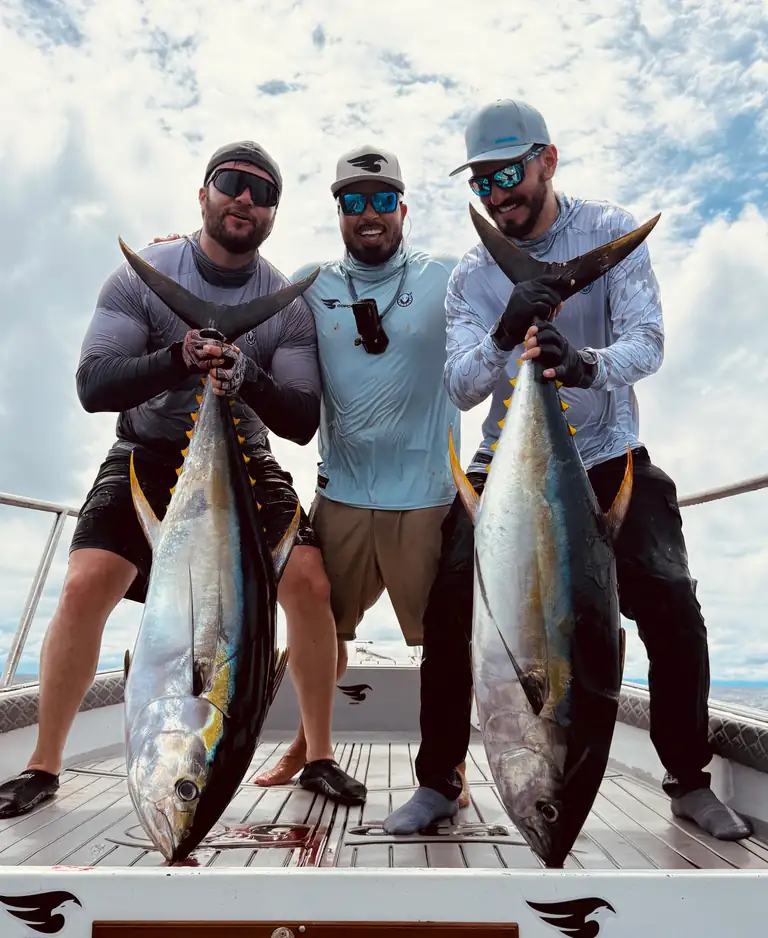 Julián Quintana con dos clientes y sus atunes aleta amarilla en la popa del bote de COFCO